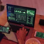 Pessoa trabalhando com software de cibersegurança em um laptop e um smartphone.