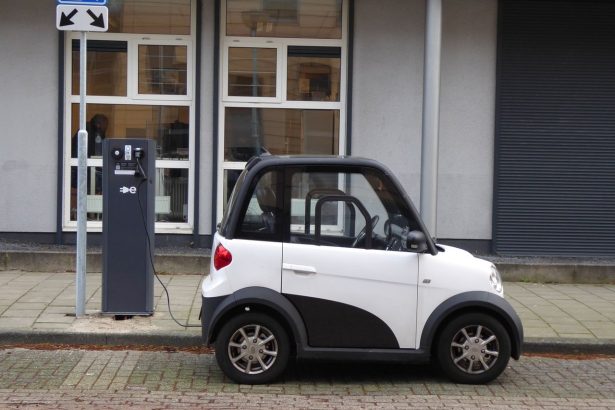 Carro elétrico compacto branco e preto conectado a uma estação pública de recarga.
