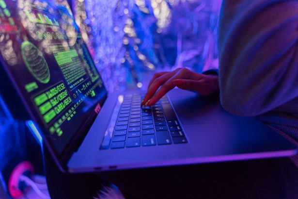 Mãos digitando em um laptop com gráficos de cibersegurança iluminados por luz roxa.