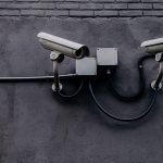 Câmera de vigilância instalada em uma parede, usada para monitoramento de segurança.