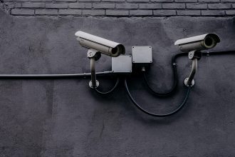 Câmera de vigilância instalada em uma parede, usada para monitoramento de segurança.
