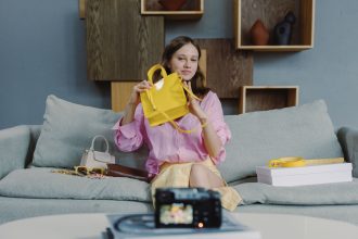 Criadora apresenta uma bolsa amarela durante uma transmissão ao vivo de venda de moda.