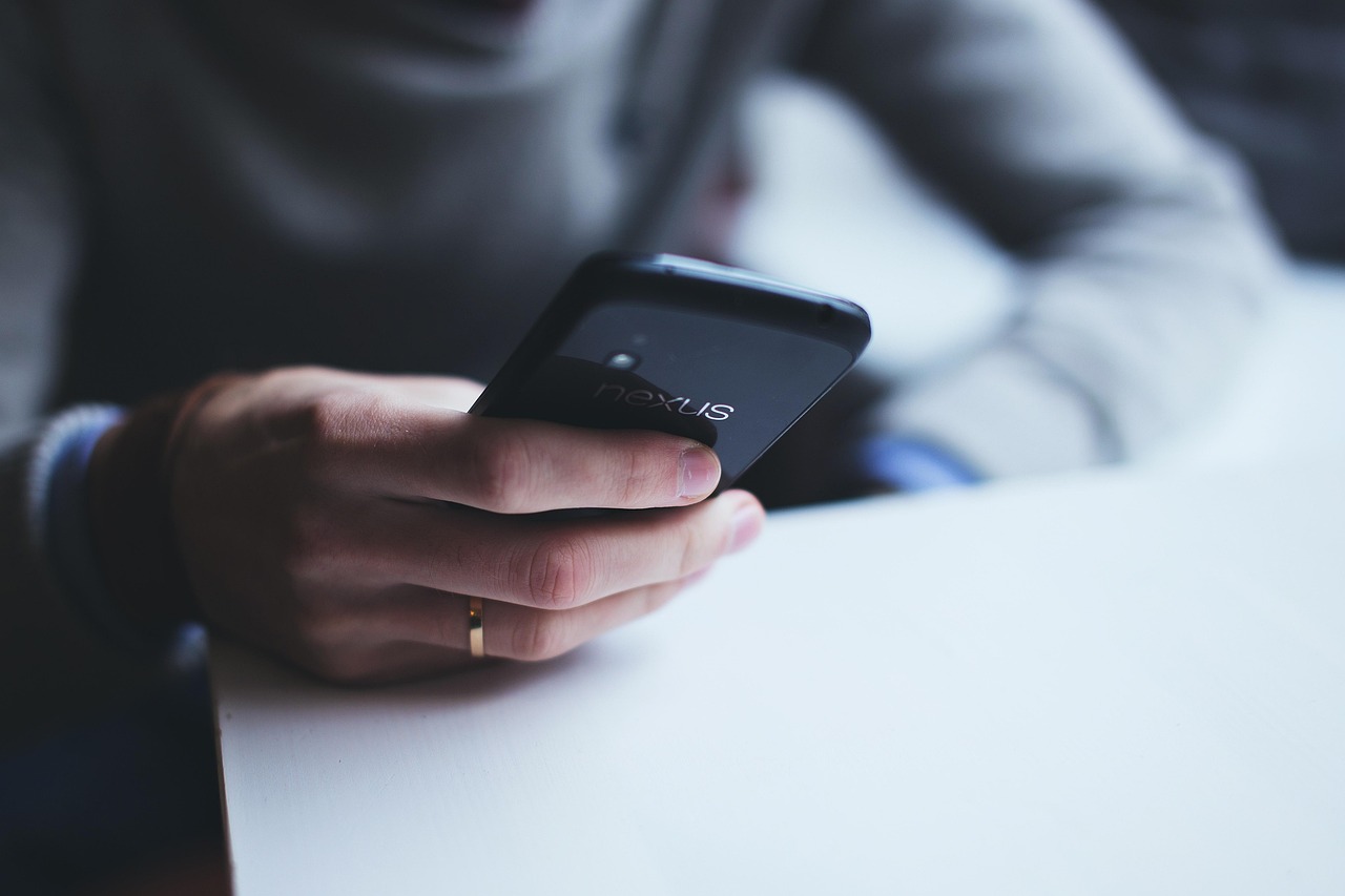 Mão de uma pessoa segurando um smartphone, em contexto de consulta digital a benefício social.